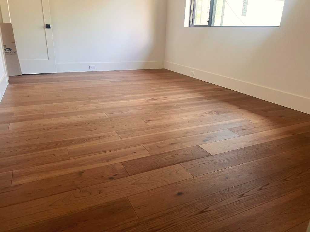 Master suite with natural oak wide plank hardwood flooring by CRG Flooring